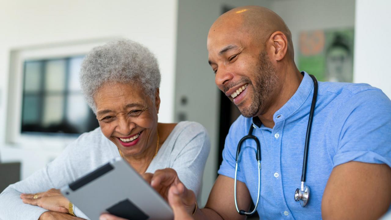 Young African-American doctor reviewing a tablet with an older African-American patient