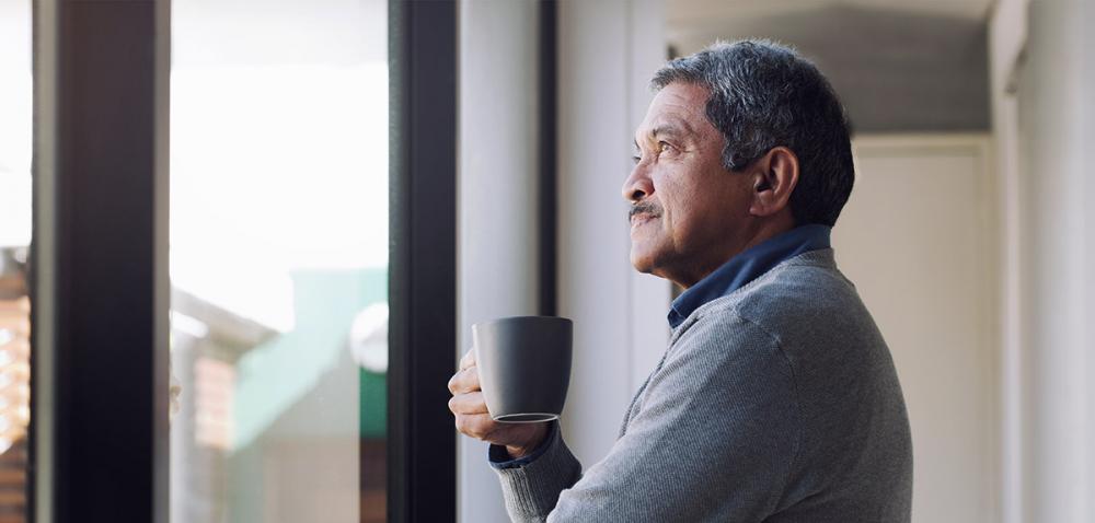 Hispanic Man Drinking Coffee Looking Out a Window